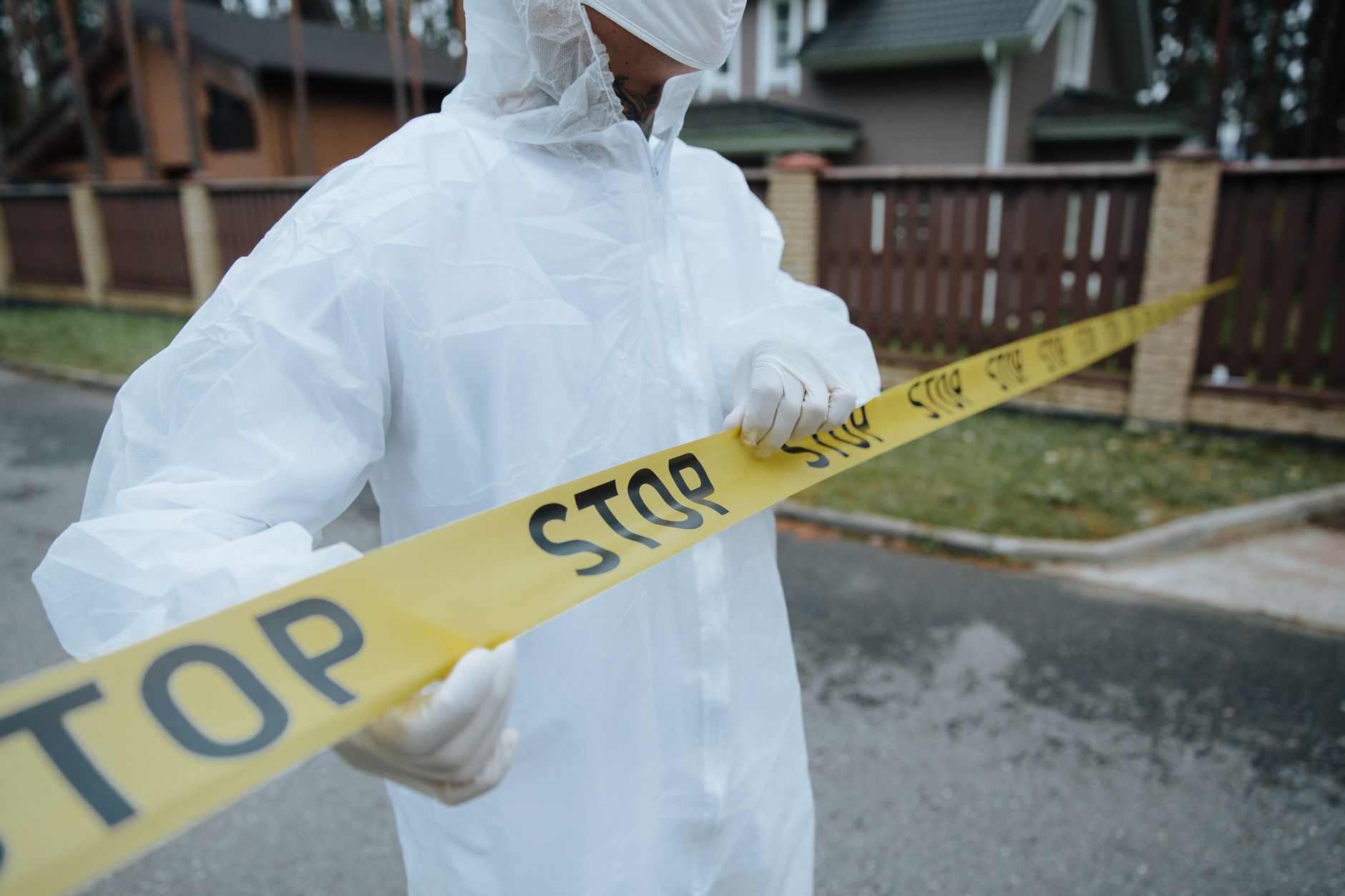 man in a protective suit guarding a tape fenced crime scene